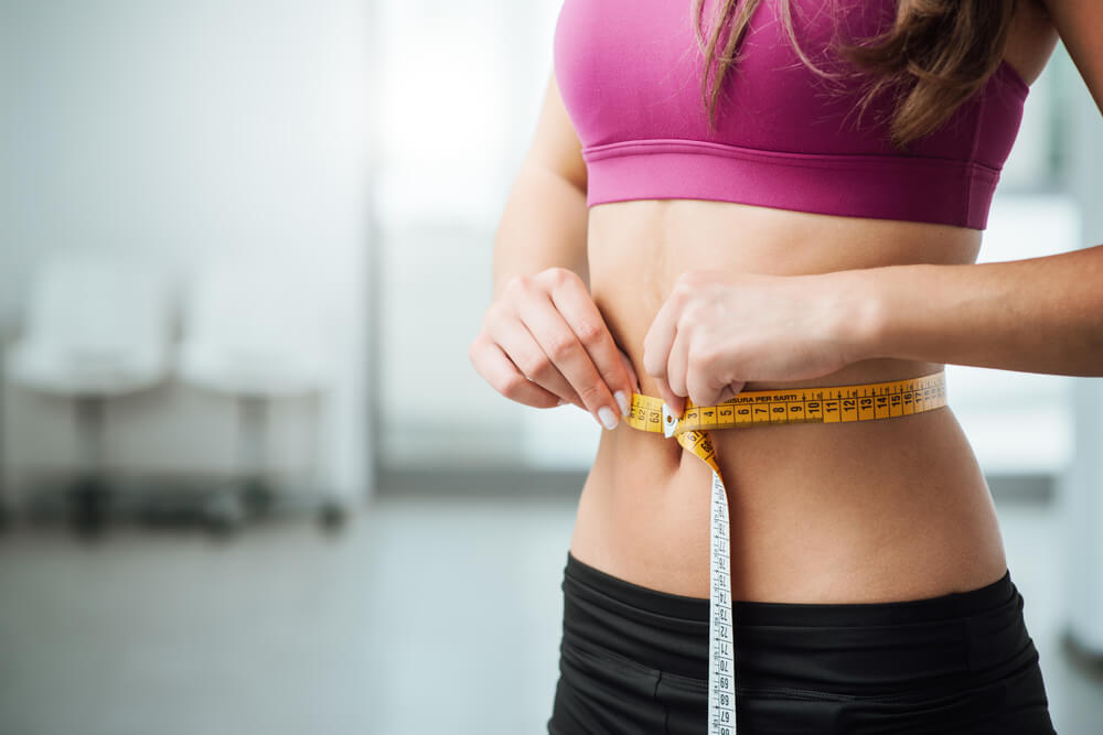 Una donna magra misura la sua circonferenza al giro vita.