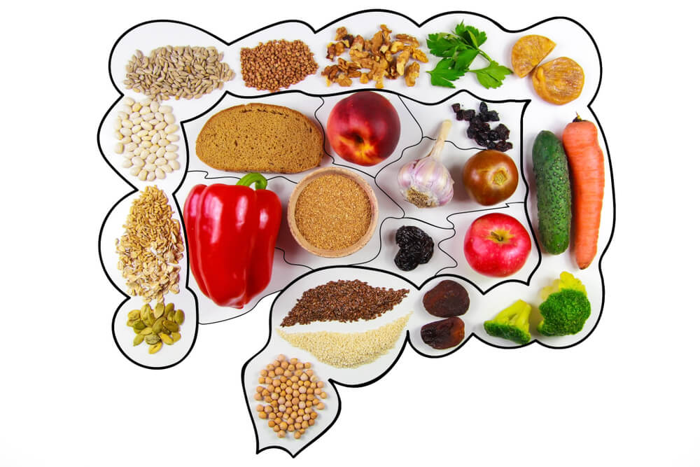 Cibo salutare per l'intestino: mele, cetrioli, fibre, frutta secca, arachidi, peperoni, pane integrale, cereali, broccoli e dei semi di lino isolati.