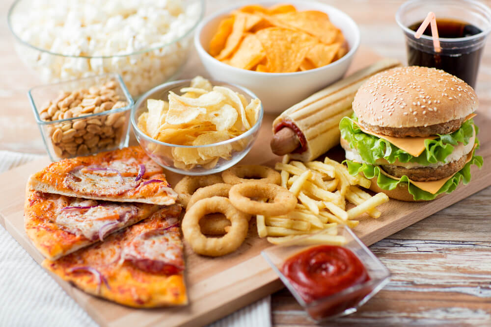 Cibi poco salutari di un fast food: cibi fritti, pizza, hamburger, stuzzichini salati, salse piccanti.