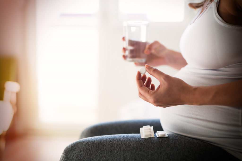 Eine schwangere Frau nimmt Tabletten gegen Sodbrennen.