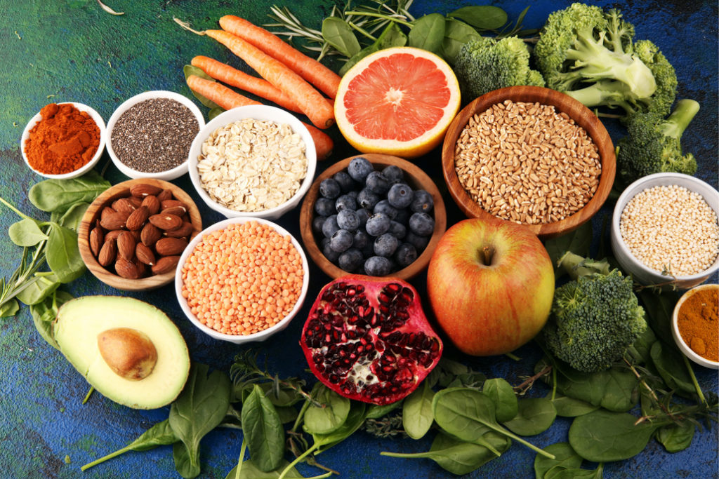 Здоровая и веганская еда на листьях шпината: фрукты, овощи, семена, суперпродукты и злаки.