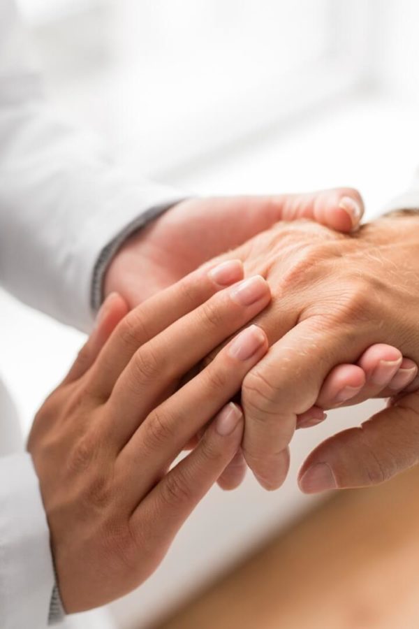 A doctor is compassionately holding the hand of an elderly patient.