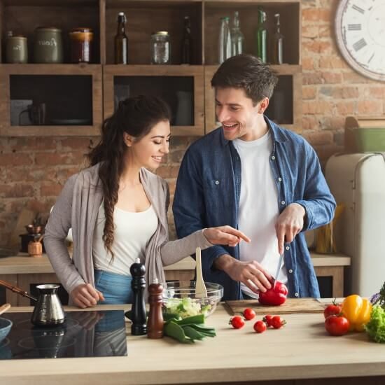 A happy young couple is cooking together in their kitchen.