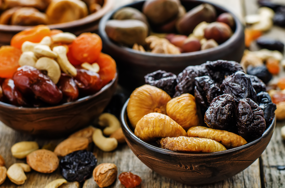 Mješavina sušenog voća i orašastih plodova u drvenim posudama na drvenom stolu.