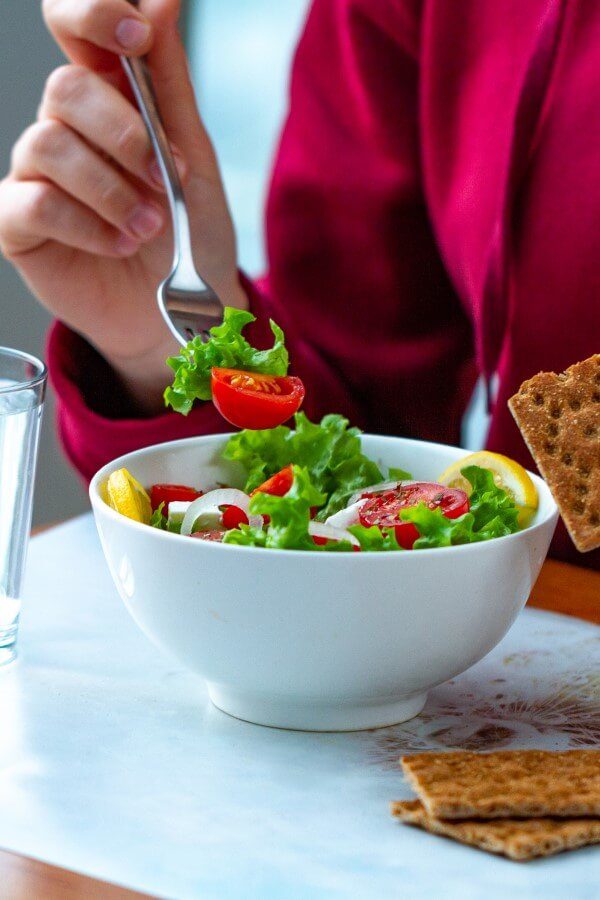 An employee is having lunch at his workplace – a salad and crackers.