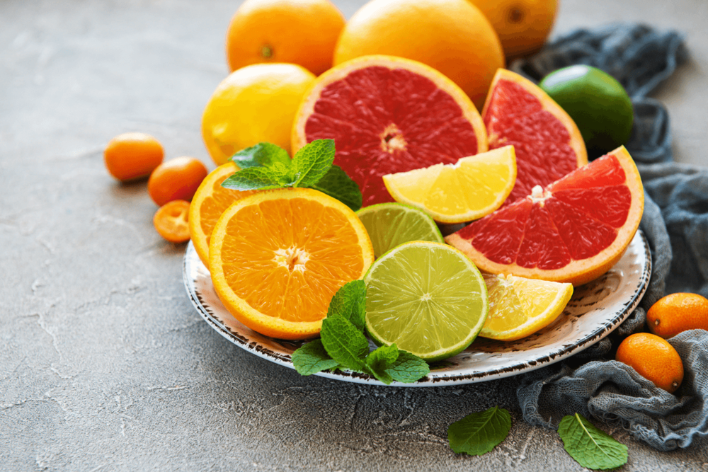 In Hälften geschnittene Zitrusfrüchte auf einem Teller: Orangen, Limetten, Zitronen, Blutorangen.