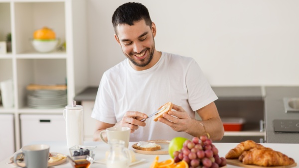 Moški se smeji ob pripravi zdravega zajtrka.