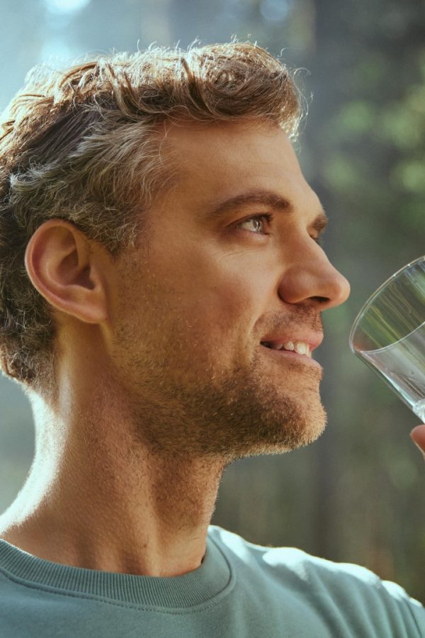 L'uomo beve acqua da un bicchiere.