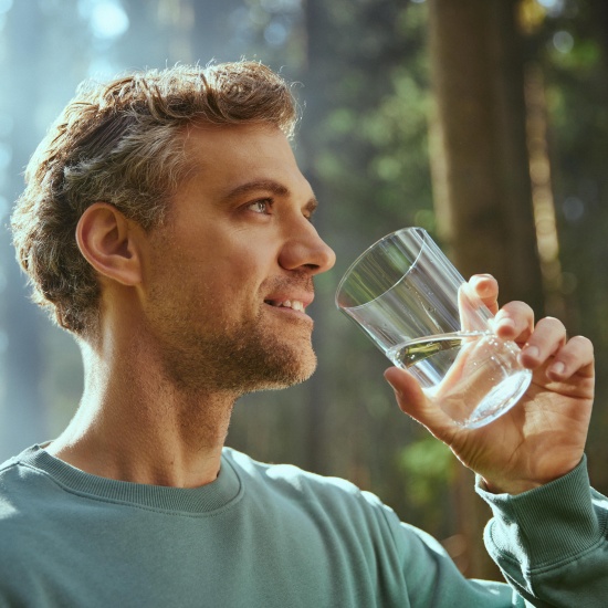 The man drinks water from a glass.