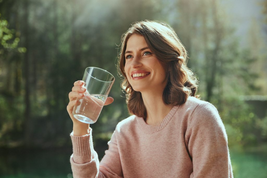 Una donna tiene in mano un bicchiere d'acqua.