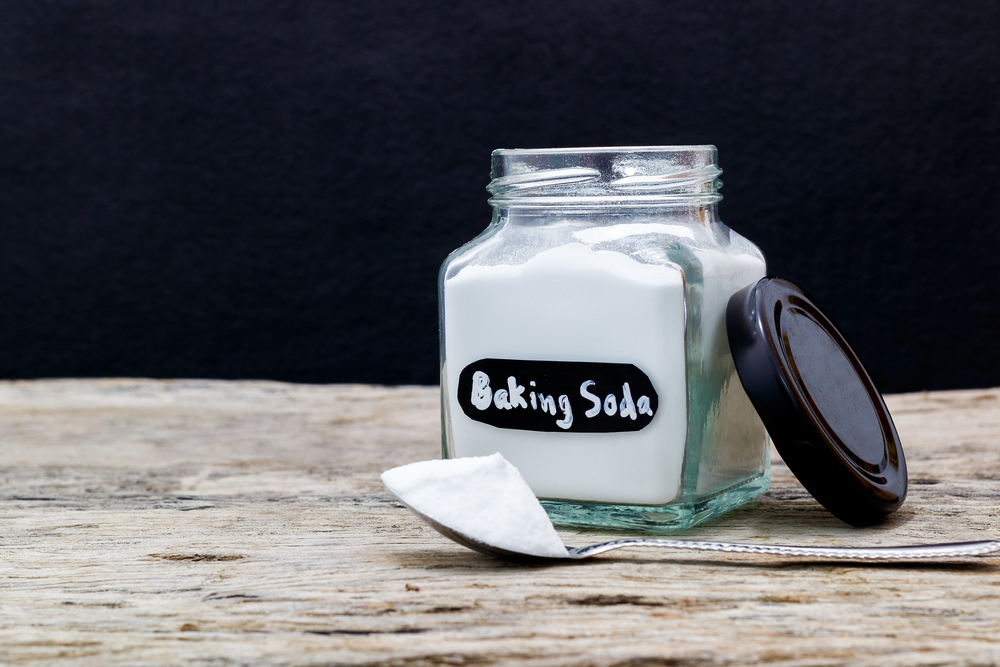 Baking soda on a spoon and in a glass jar for filing.