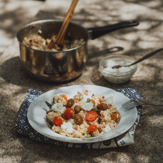 Salata od riže sa šparogama na keramičkom tanjuru.